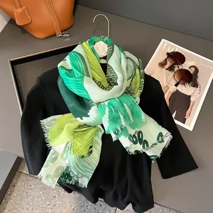 Détail d'une écharpe à imprimé feuilles vertes avec bords effilés et accessoires mode