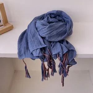 Detail of blue cotton-linen scarf showing pleated texture and multicolor tassel fringe