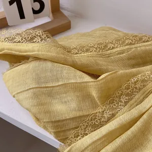 Detail of ginger yellow cotton scarf showing crinkled texture and delicate lace edge