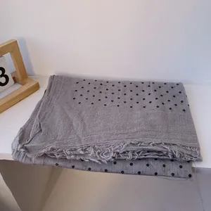 Detail of gray linen scarf with black polka dots and natural frayed fringe edges