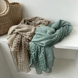 Detail van linnen sjaal met fijne kanten opengewerkte randen in beige en saliegroen