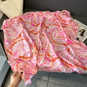 Dettaglio di sciarpa tie-dye rosa con bordi a frange e trama leggera estiva