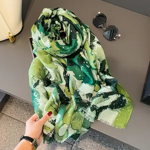 Detail of green abstract ink print scarf with gold sequins and soft fringe edges