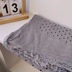 Detail of grey polka dot linen scarf with frayed edges and soft breathable texture