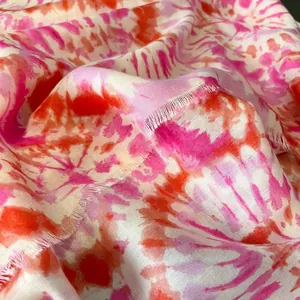 Dettaglio di sciarpa tie-dye leggera rosa e arancione con bordi sfrangiati naturali