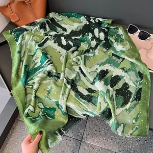 Detail of green oil painting style scarf with gold powder accents and frayed edges