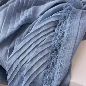 Close-up of light blue pleated cotton scarf fabric with delicate lace embroidery details