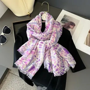 Dettaglio dello scialle tie-dye viola con frange su maglieria nera per protezione solare
