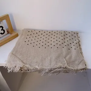 Detail of beige linen polka dot scarf showing fine fabric texture and fringed edges