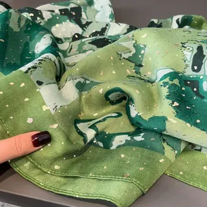Detailed macro of green oil painting silk scarf with golden glitter and fine stitching