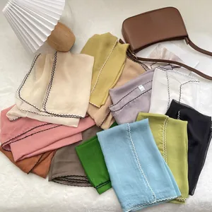 Detail of colorful lightweight scarves with delicate scalloped wavy embroidered edges