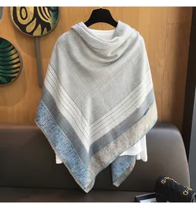 Detail of grey plaid scarf with blue stripes and fringe edges over a white shirt
