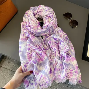 Dettaglio macro di sciarpa tie-dye viola con frange su tavolo con occhiali da sole