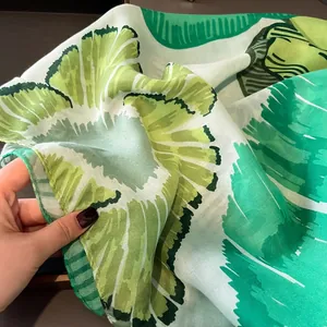 Détail d'une écharpe en soie légère avec texture à imprimé de feuilles vertes