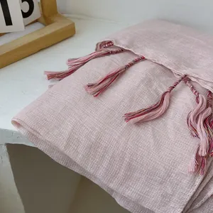 Close-up of light pink linen scarf featuring delicate fringe and woven texture