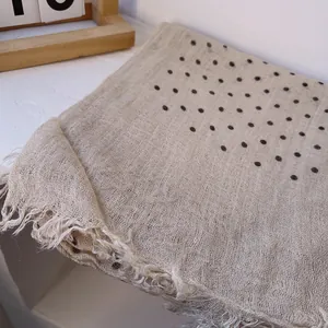 Detail of beige linen polka dot scarf showing lightweight texture and fringe edges
