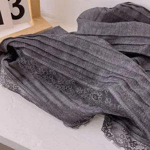 Close-up of pleated dark grey cotton scarf featuring delicate black eyelash lace trim