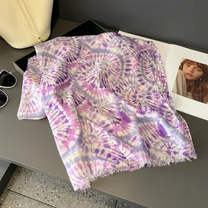 Dettaglio di una sciarpa leggera tie-dye viola con bordi sfrangiati e motivo a spirale trendy