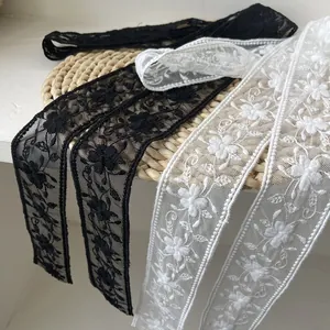 Détail de broderie florale sur rubans de dentelle noir et blanc à bords festonnés