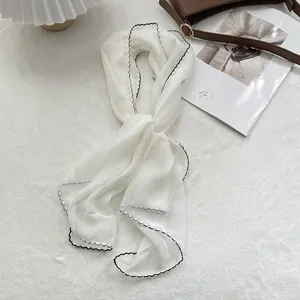 Macro shot of white chiffon scarf featuring elegant black ruffled wave edges