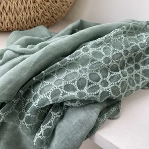 Detailopname van saliegroene linnen sjaal met delicate opengewerkte kanten bloemen