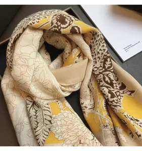 Detailed view of floral patterns on a lightweight silk-like yellow and beige scarf