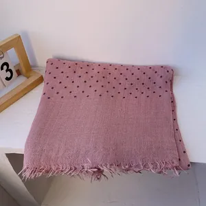 Macro detail of soft pink linen scarf with small dark polka dots and frayed fringe edges