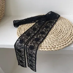 Gros plan d'un foulard en dentelle florale noire sur un tapis tissé aux broderies fines