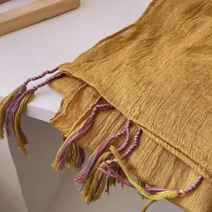 Detail of ginger cotton linen scarf featuring crinkle texture and multicolored tassels