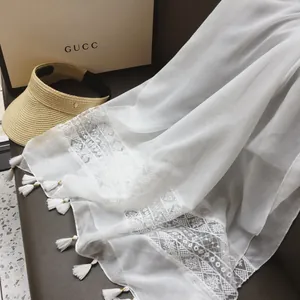 White ethnic lace scarf with tassels and straw sun hat on a premium leather background