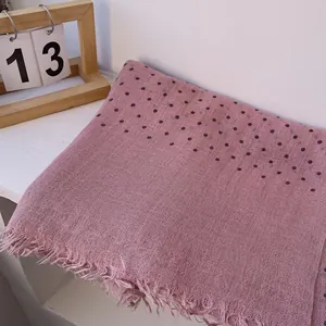 Close-up of pink linen scarf with dark blue polka dots and natural frayed edges
