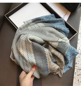 Close-up of geometric plaid scarf with blue and beige stripes and fine fringe detail