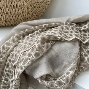 Macro-detail van beige katoenen sjaal met bloemenkant en zachte textuur van de stof