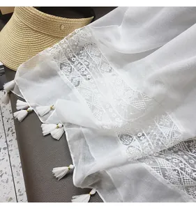 Detail of white lace shawl with ethnic embroidery patterns and delicate tassel fringes