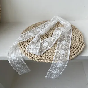 Détail de ruban de dentelle florale blanche avec broderie sur un tapis en paille
