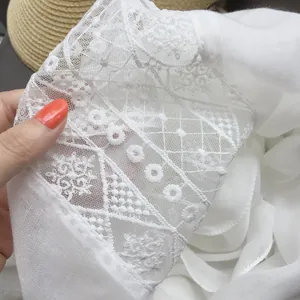 Close-up detail of white ethnic style scarf with delicate lace embroidery and floral patterns