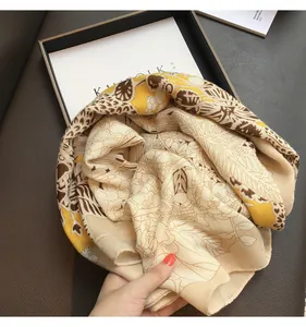 Detailed view of floral silk scarf with yellow patterns in a black display box