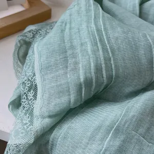 Detail of mint green scarf with pleated texture and delicate lace embroidery edges