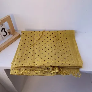 Close-up of lightweight yellow linen scarf with black polka dots and frayed fringe edges