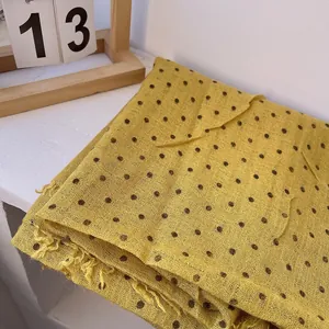 Close-up of yellow linen scarf with dark polka dots and delicate fringe detail