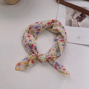 Detail eines geblümten Baumwollhalstuchs mit gelber Ziernaht auf weißem Hintergrund
