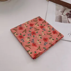 Detail eines weichen Baumwoll-Bandanas mit korallenrosa Stoff und kleinem Blumenmuster