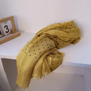 Detail of yellow linen scarf with black polka dots featuring delicate frayed edges
