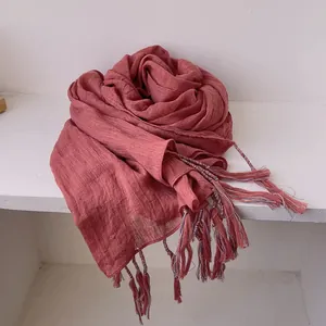 Detailed texture of brick red cotton linen scarf with soft fringe and pleated fabric
