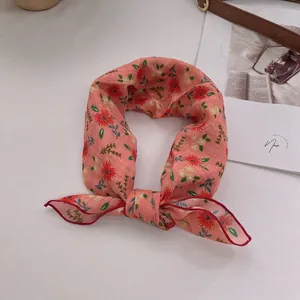 Detailansicht eines floralen Baumwolltuches mit orangefarbener Basis und Knotenschleife