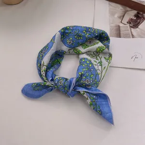 Close-up of sky blue cotton linen scarf with floral patterns and purple stitched edges