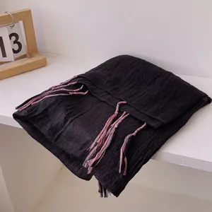 Detail of black cotton linen scarf showing pleated texture and colorful tassel fringe
