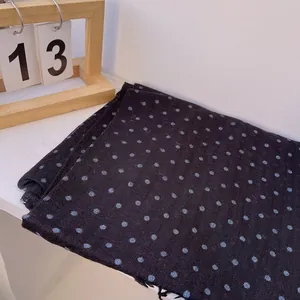 Detail of linen texture on black polka dot scarf with frayed edges and blue dots