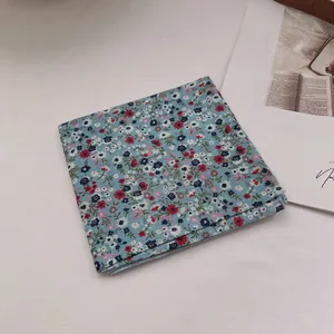 Detail of light blue floral cotton linen bandana folded on a white textured background