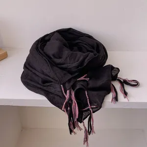 Detail of black cotton linen scarf showing colorful woven tassels and textured fabric